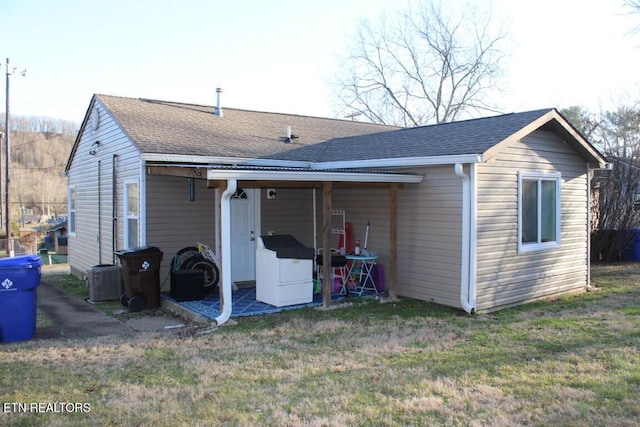 back of property with a lawn and a shingled roof