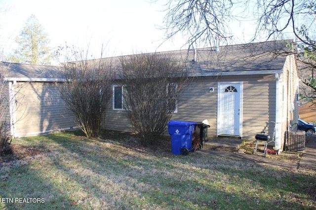 rear view of property featuring cooling unit, a lawn, and a shingled roof