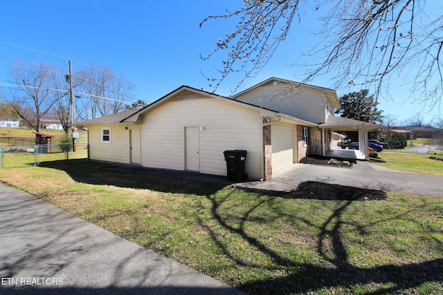 view of property exterior with brick siding, a lawn, an attached garage, and fence