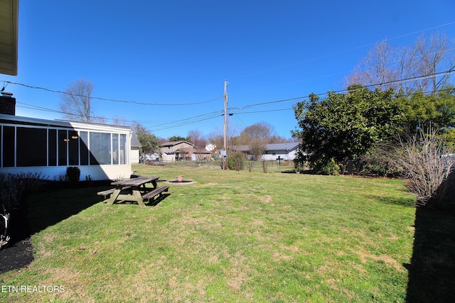 view of yard featuring a fire pit, fence, and a sunroom