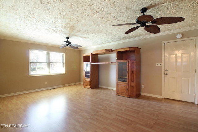 unfurnished living room with a textured ceiling, light wood-style floors, baseboards, and crown molding