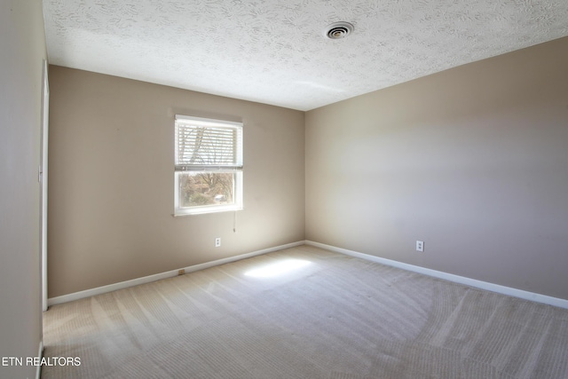 spare room with carpet, visible vents, baseboards, and a textured ceiling