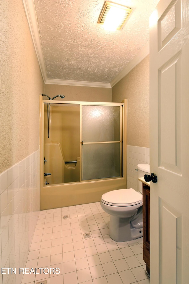 bathroom featuring tile walls, visible vents, a textured ceiling, and combined bath / shower with glass door