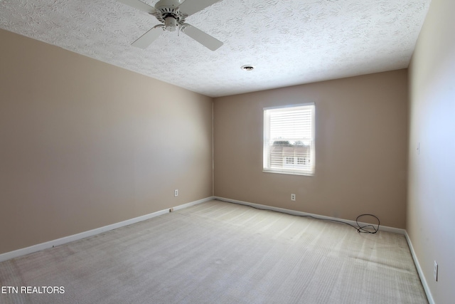 spare room featuring light carpet, ceiling fan, a textured ceiling, and baseboards