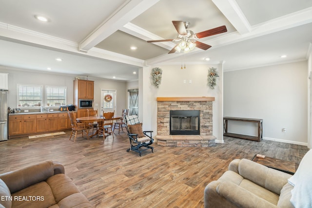 living room with crown molding, a stone fireplace, wood finished floors, beamed ceiling, and baseboards