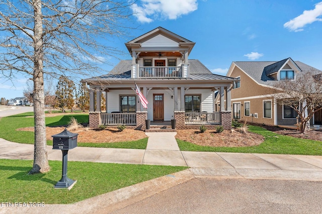 view of front facade featuring a balcony, metal roof, covered porch, a standing seam roof, and a front yard