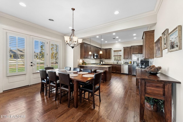 dining space with crown molding, visible vents, and dark wood finished floors