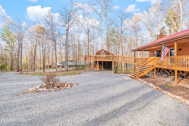 view of yard with a deck, stairs, and gravel driveway