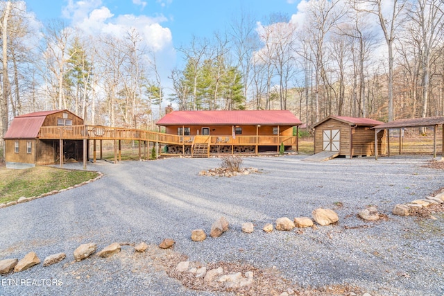 rustic home featuring an outbuilding, a gambrel roof, a storage shed, and a deck