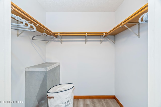 walk in closet with wood finished floors