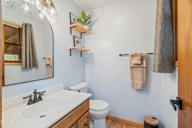 bathroom with baseboards, toilet, and vanity