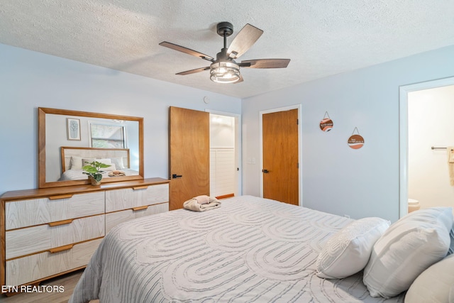 bedroom featuring a textured ceiling, ensuite bathroom, ceiling fan, and wood finished floors