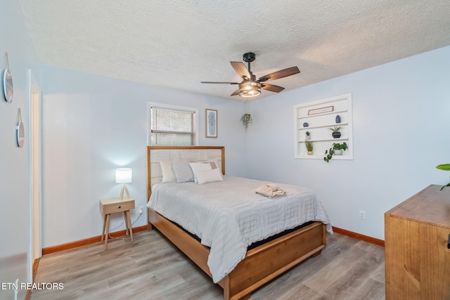 bedroom featuring a ceiling fan, wood finished floors, baseboards, and a textured ceiling