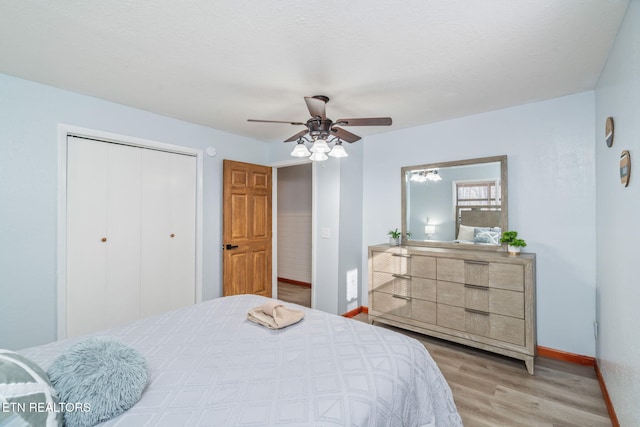 bedroom featuring a ceiling fan, visible vents, baseboards, light wood-style flooring, and a closet