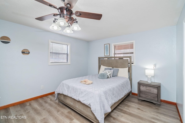 bedroom with a ceiling fan, baseboards, and light wood finished floors