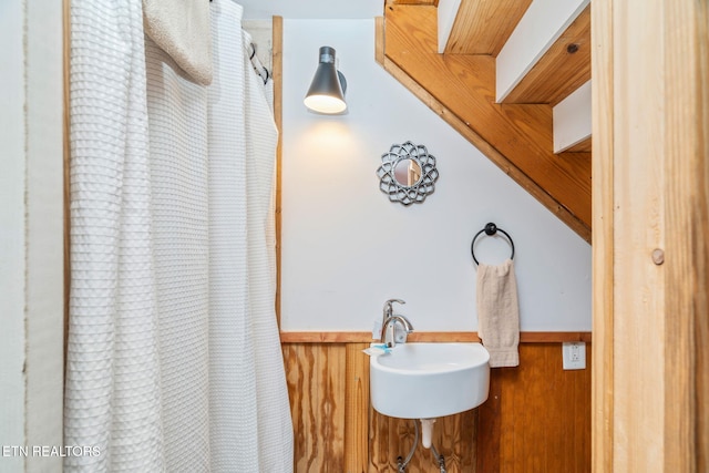 bathroom featuring a sink, a wainscoted wall, curtained shower, and wood walls