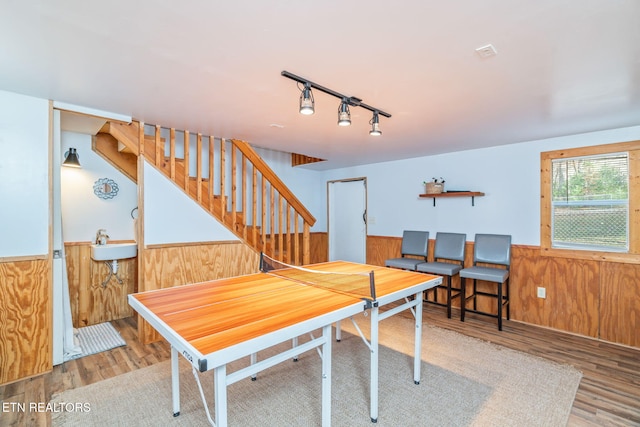 dining space with a wainscoted wall, track lighting, wood finished floors, wood walls, and stairs