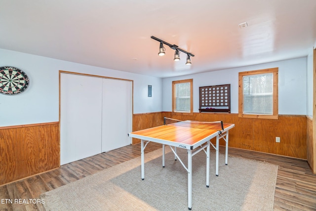 rec room featuring a wainscoted wall, wooden walls, and wood finished floors