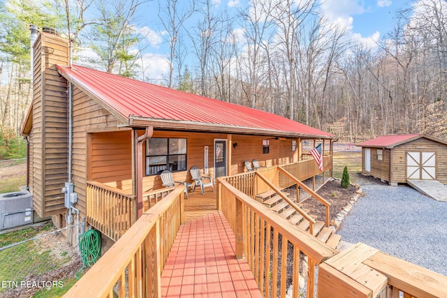 wooden terrace featuring an outbuilding, covered porch, cooling unit, and a storage shed