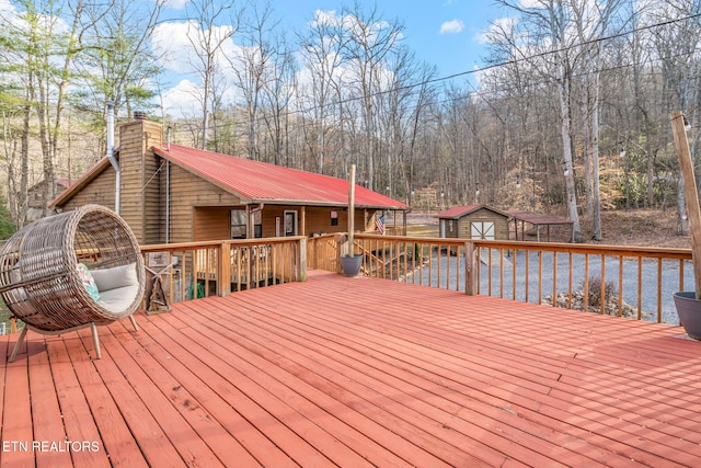 wooden deck with a view of trees and an outdoor structure