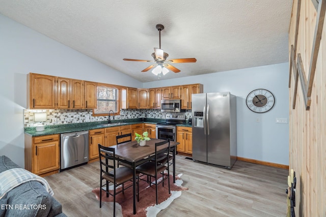 kitchen with a sink, dark countertops, light wood-style floors, and stainless steel appliances