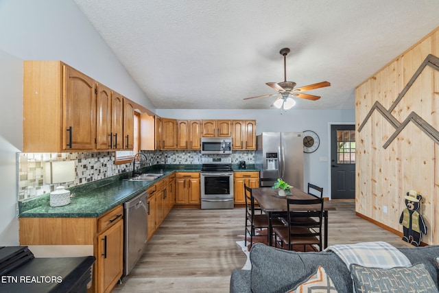 kitchen featuring a sink, tasteful backsplash, appliances with stainless steel finishes, and light wood-style flooring