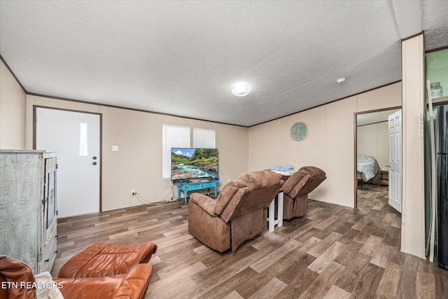 living area with ornamental molding, a textured ceiling, and wood finished floors