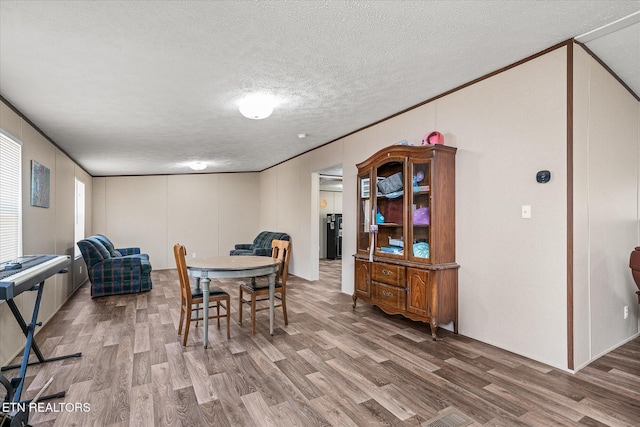 dining space featuring a textured ceiling, wood finished floors, and crown molding