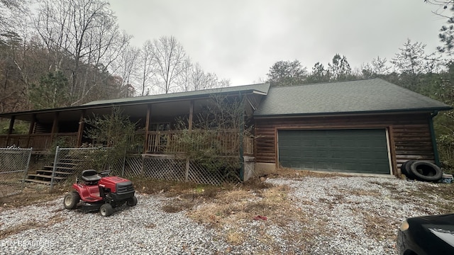 view of front facade featuring a garage, a porch, gravel driveway, and roof with shingles