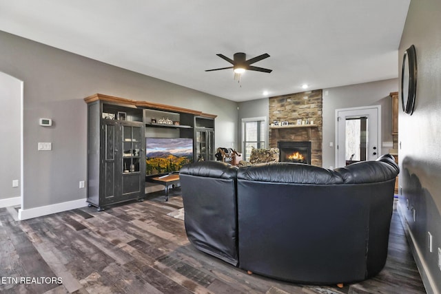 living area featuring a ceiling fan, dark wood-style flooring, a fireplace, and baseboards