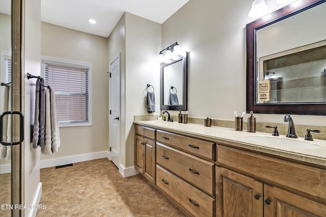 full bath featuring double vanity, baseboards, a sink, and tile patterned floors