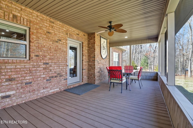 wooden deck with outdoor dining area and a ceiling fan