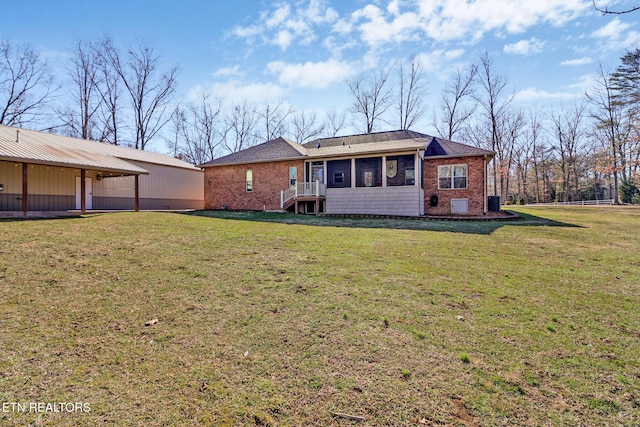 back of house featuring a yard, a sunroom, and brick siding