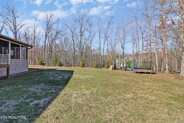 view of yard featuring a trampoline, a sunroom, and a playground