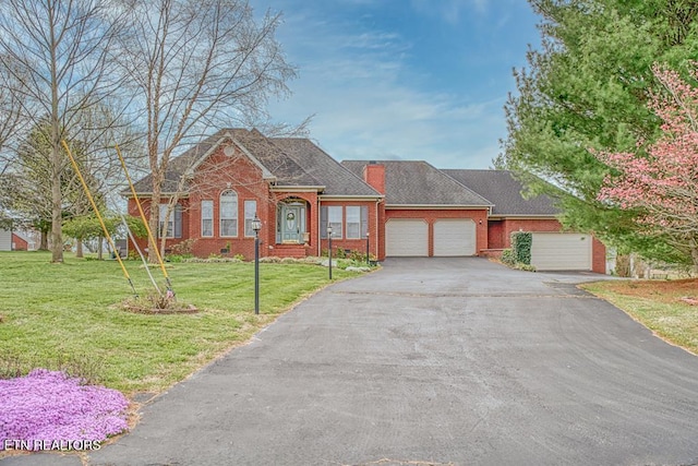 view of front of house with aphalt driveway, brick siding, a chimney, an attached garage, and a front lawn