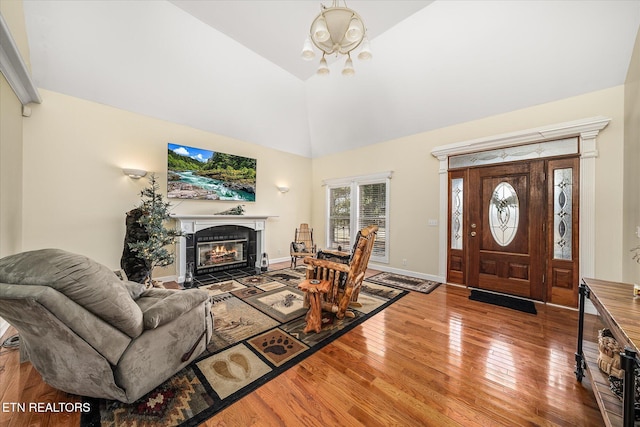 entryway featuring high vaulted ceiling, wood-type flooring, baseboards, and a tile fireplace