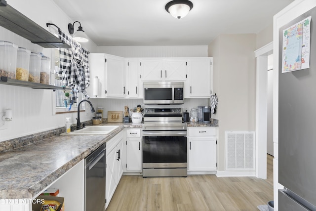 kitchen with visible vents, appliances with stainless steel finishes, light wood-style floors, white cabinets, and a sink