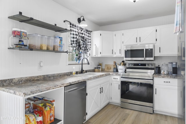 kitchen featuring a sink, white cabinets, stainless steel appliances, and open shelves