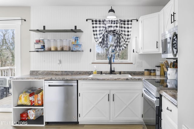 kitchen with open shelves, white cabinetry, appliances with stainless steel finishes, and a sink