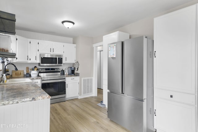 kitchen featuring visible vents, white cabinets, appliances with stainless steel finishes, and a sink