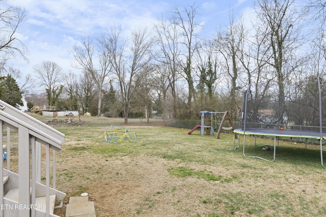 view of yard featuring a playground, a trampoline, and fence