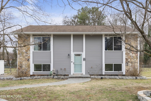 bi-level home featuring a front yard and fence