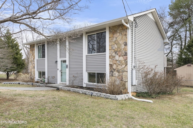 bi-level home featuring stone siding and a front lawn