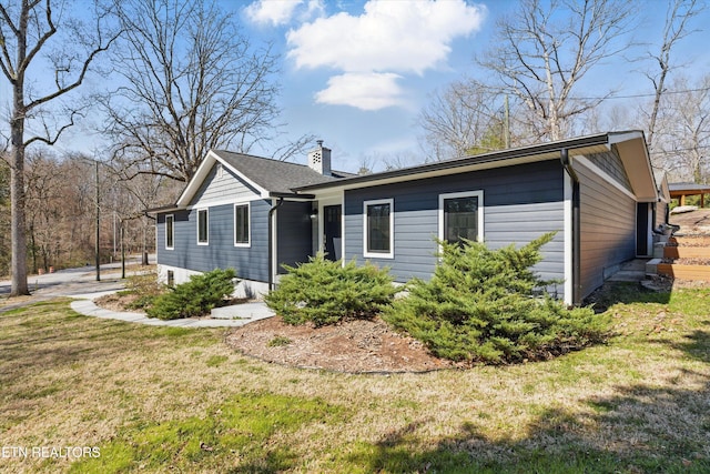 ranch-style house with a front yard and a chimney