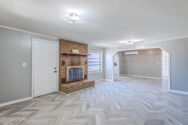 unfurnished living room with arched walkways, a brick fireplace, crown molding, and a wall mounted AC