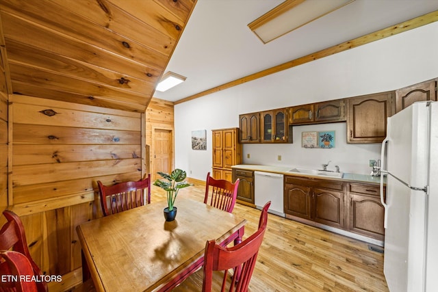 dining area with vaulted ceiling, light wood finished floors, and wooden walls