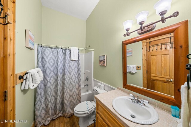 full bathroom featuring shower / bath combination with curtain, toilet, vaulted ceiling, vanity, and wood finished floors