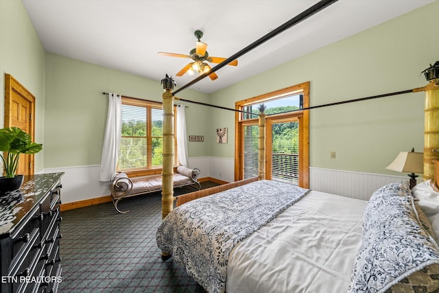 bedroom with a wainscoted wall, ceiling fan, and dark carpet