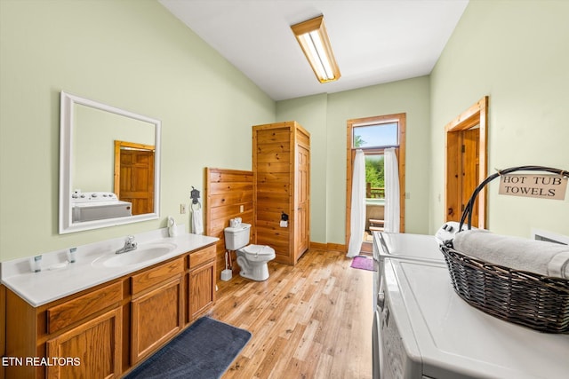 bathroom featuring toilet, vanity, wood finished floors, and washing machine and clothes dryer