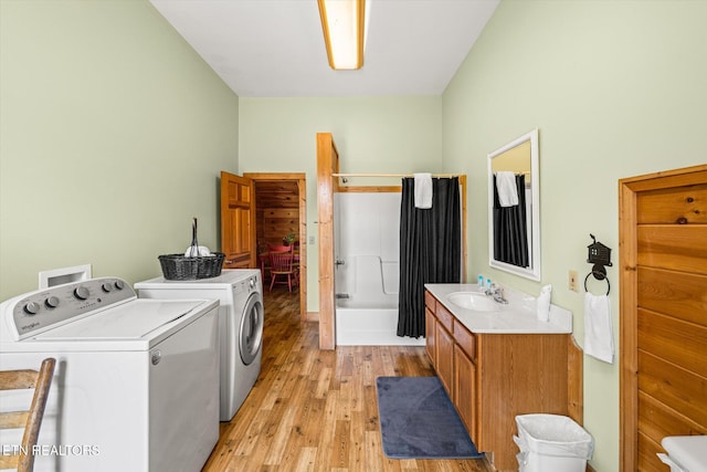 washroom with light wood finished floors, laundry area, separate washer and dryer, and a sink